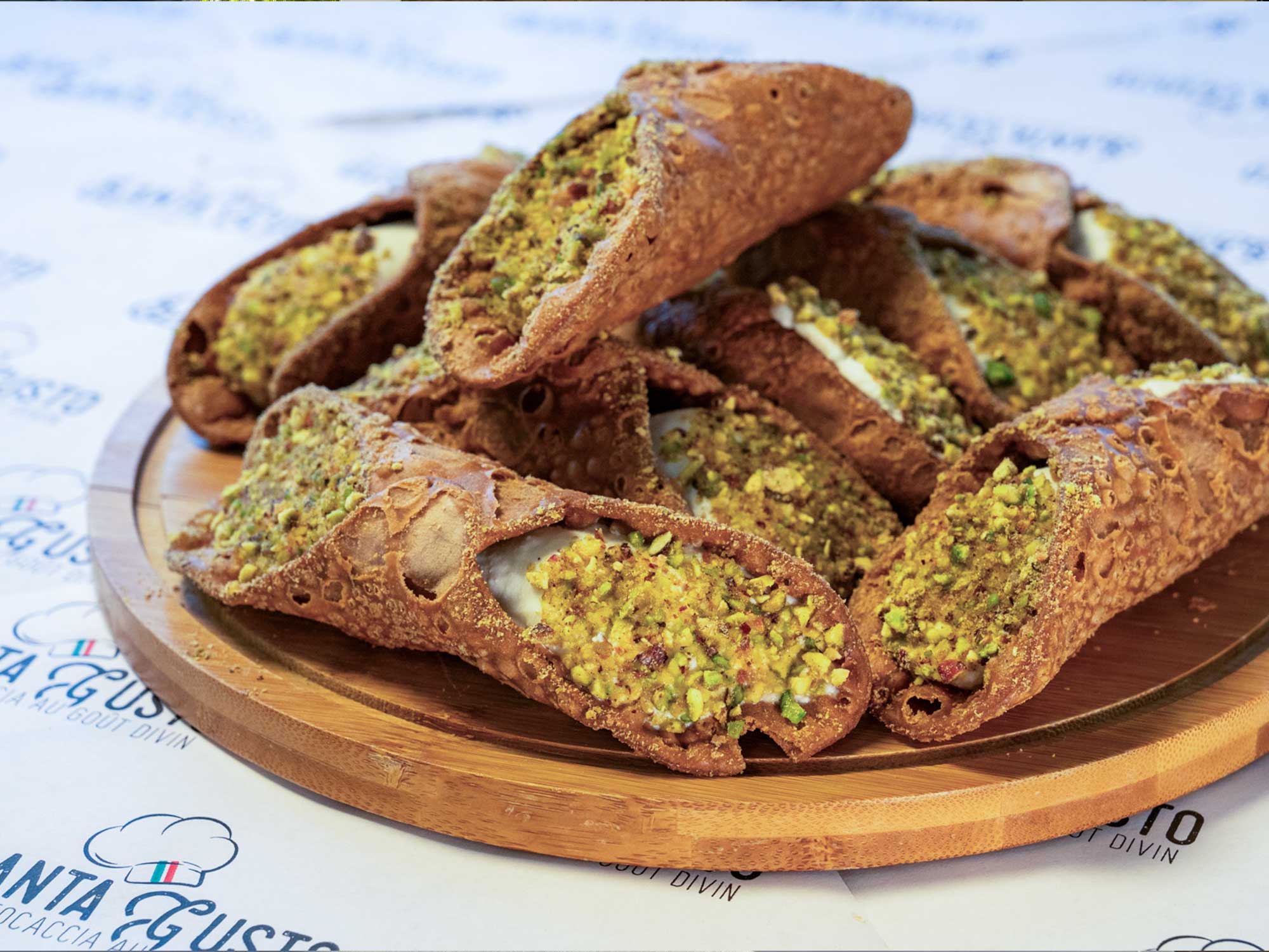 Une assiette avec des cannolis à la pistache.